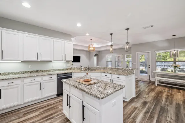 a large kitchen with granite countertop a island a sink stainless steel appliances and white cabinets