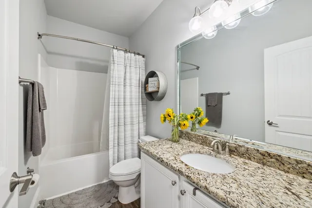 a bathroom with a granite countertop sink toilet and shower