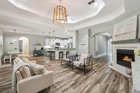 a living room with furniture a fireplace and a chandelier