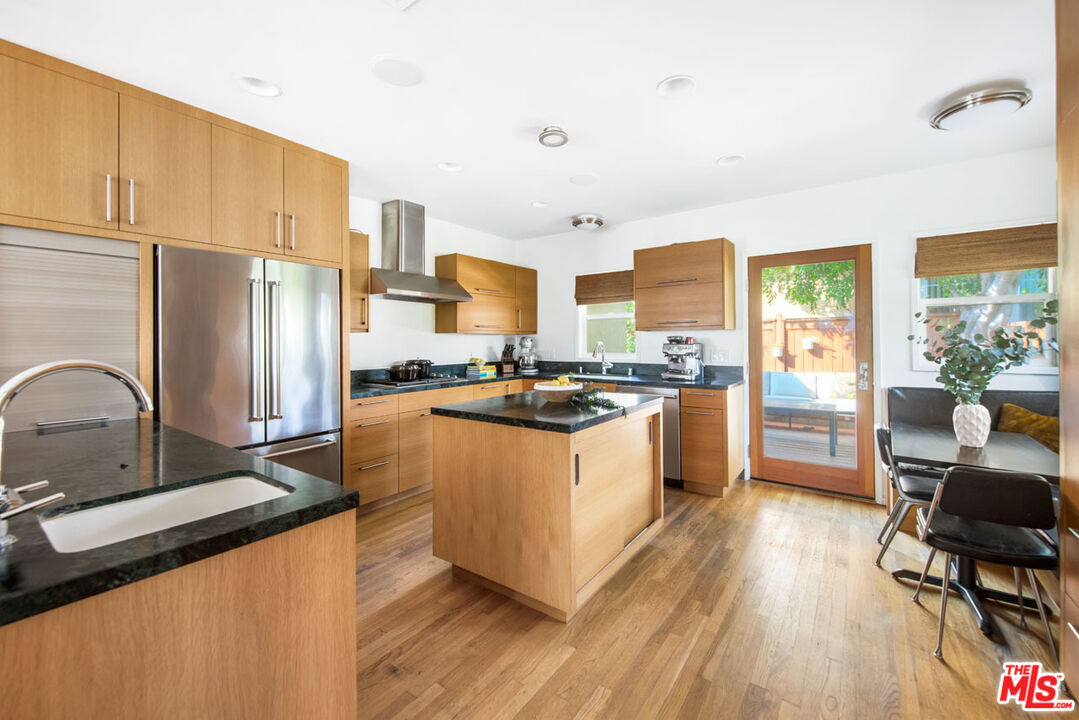 1715 Sinaloa Avenue Pasadena, CA 91104 - Photo 9 of 33 a kitchen with stainless steel appliances granite countertop a refrigerator a stove top oven a sink dishwasher and white cabinets with wooden floor
