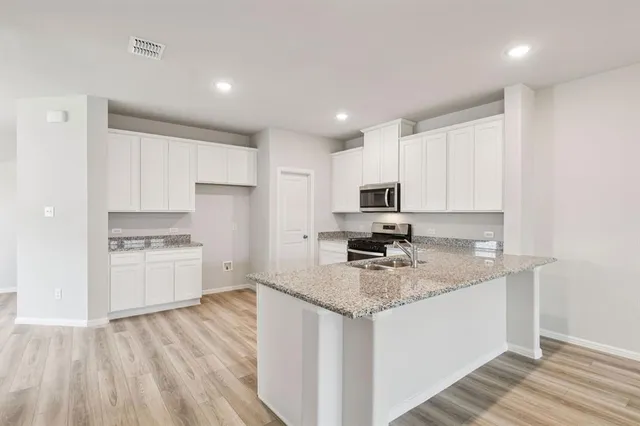 a kitchen with a sink a stove a refrigerator and white cabinets