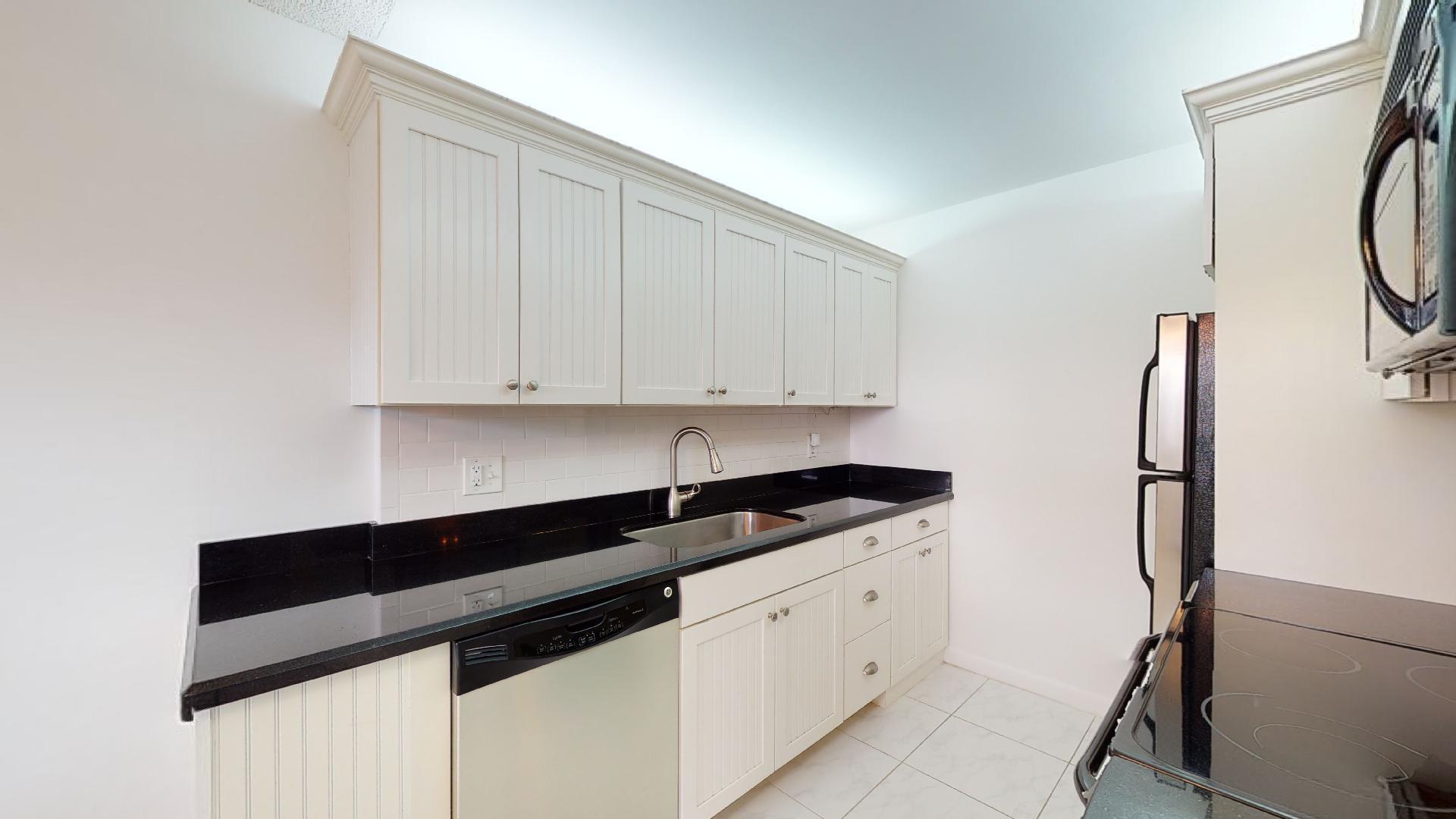 1014 Exeter Boca Raton, FL 33434 - Photo 5 of 31 a kitchen with granite countertop white cabinets and white appliances