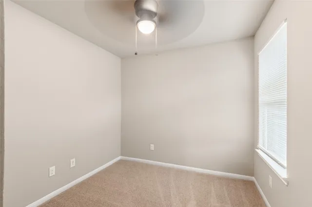 an empty room with a chandelier fan and windows