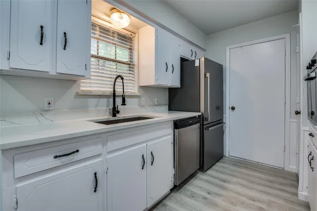 a kitchen with stainless steel appliances a sink cabinets and a window