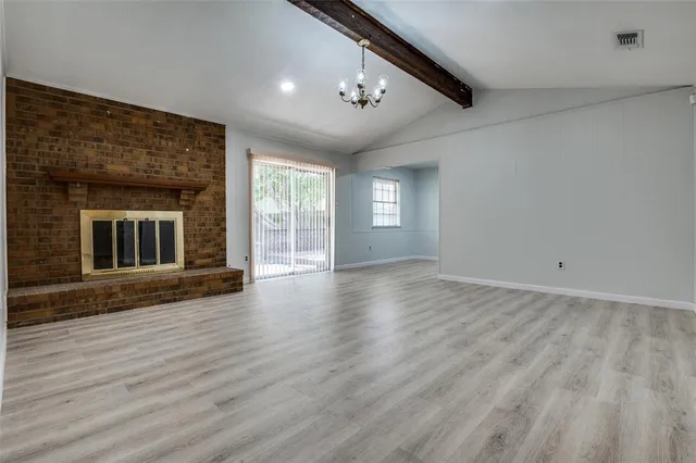 a view of an empty room with wooden floor and a fireplace