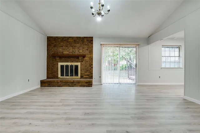 a view of an empty room with wooden floor and a fireplace