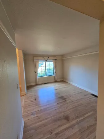 an empty room with wooden floor fireplace and windows