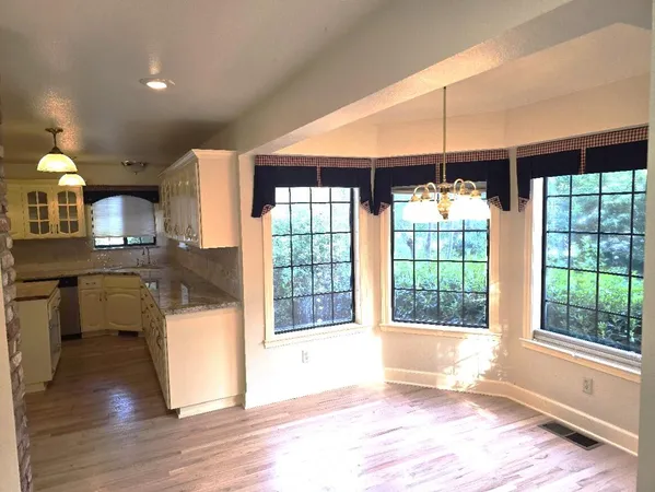 a view of a room that has a large window and wooden floor