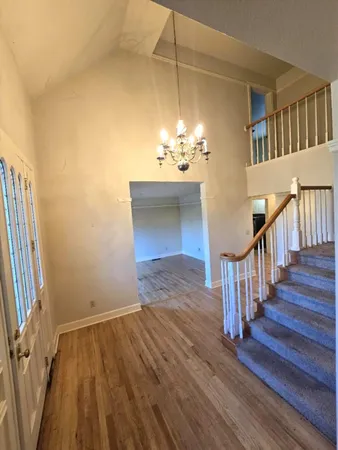 an empty room with wooden floor fireplace and windows