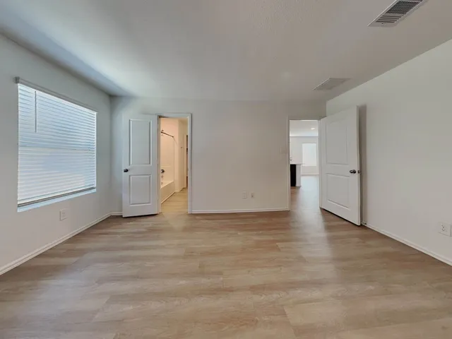 an empty room with wooden floor and windows