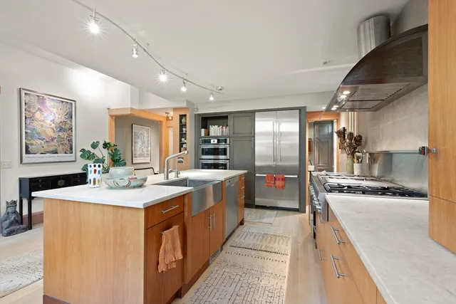a large kitchen with stainless steel appliances a sink and cabinets