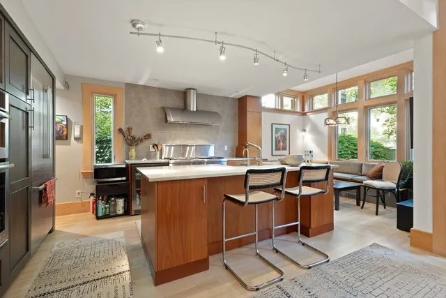 a living room with stainless steel appliances granite countertop furniture a rug kitchen view and large windows