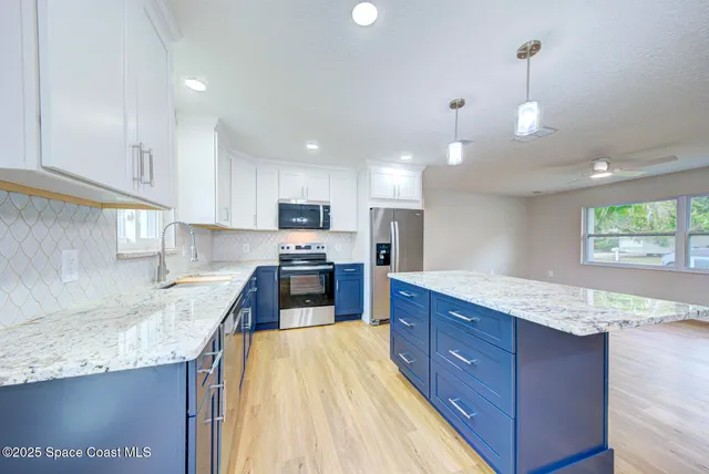 a kitchen with granite countertop a sink a counter top space appliances and cabinets