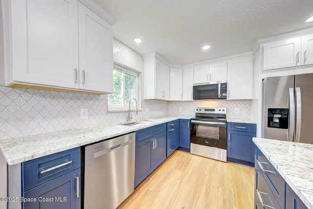 a kitchen with stainless steel appliances granite countertop a sink dishwasher stove and refrigerator