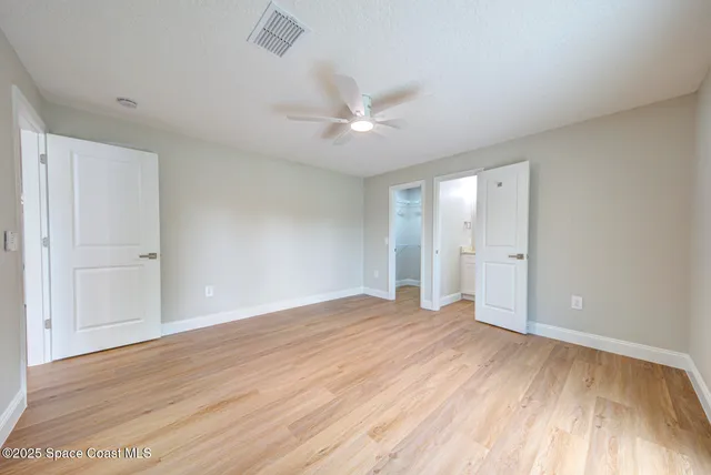 a view of an empty room and window a ceiling fan and wooden floor