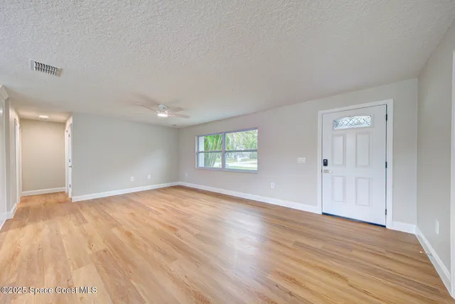 an empty room with wooden floor and windows