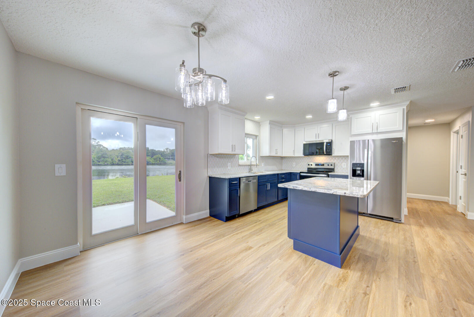 3733 Crossbow Drive Cocoa, FL 32926 - Photo 9 of 25 a large kitchen with stainless steel appliances granite countertop a refrigerator a oven a dining table and chairs with wooden floor
