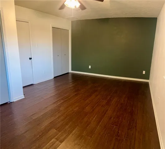 an empty room with wooden floor and chandelier fan