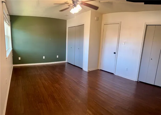 an empty room with wooden floor and fan
