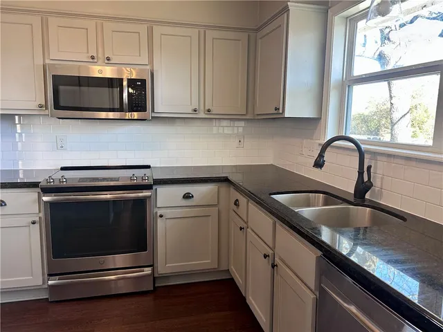 a kitchen with stainless steel appliances granite countertop a stove microwave and sink