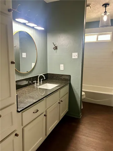 a bathroom with a granite countertop sink a mirror and a bathtub