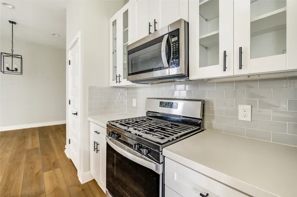 a kitchen with kitchen island wooden floors appliances and cabinets