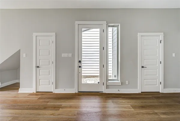 an empty room with wooden floor closet and windows