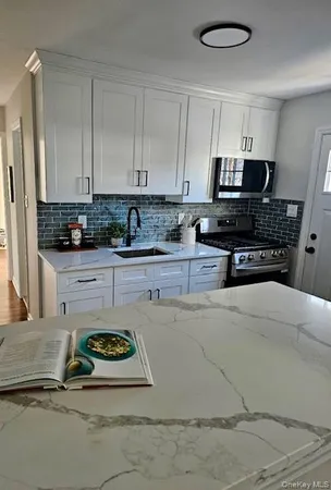 a kitchen with kitchen island granite countertop a sink a stove a oven a refrigerator and white cabinets