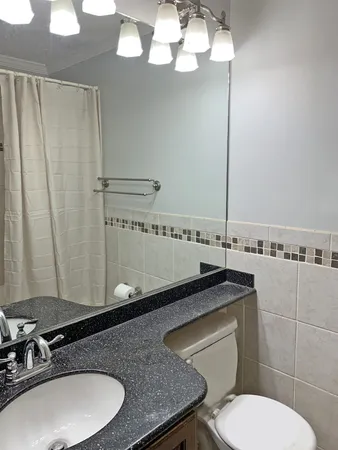 a bathroom with a granite countertop toilet sink and mirror