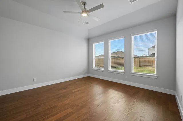 a view of an empty room with wooden floor and a window