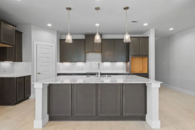a kitchen with kitchen island a counter top space a sink and stainless steel appliances