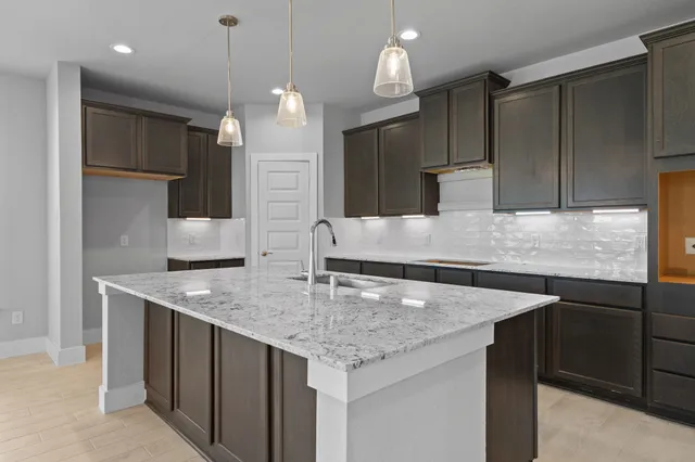 a kitchen with stainless steel appliances granite countertop a kitchen island a refrigerator and a sink