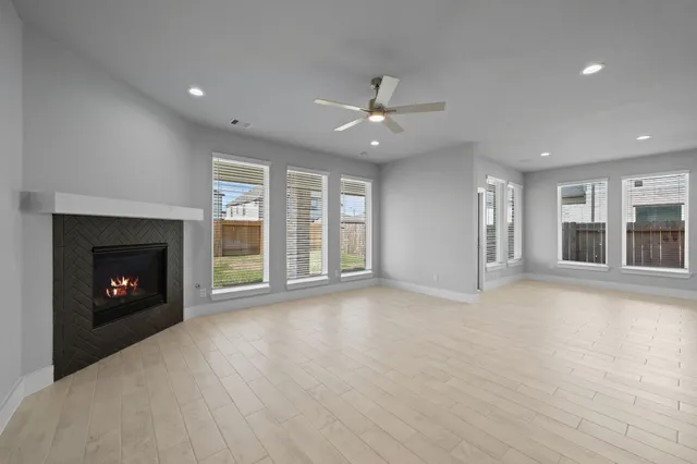 an empty room with windows fireplace and a kitchen view