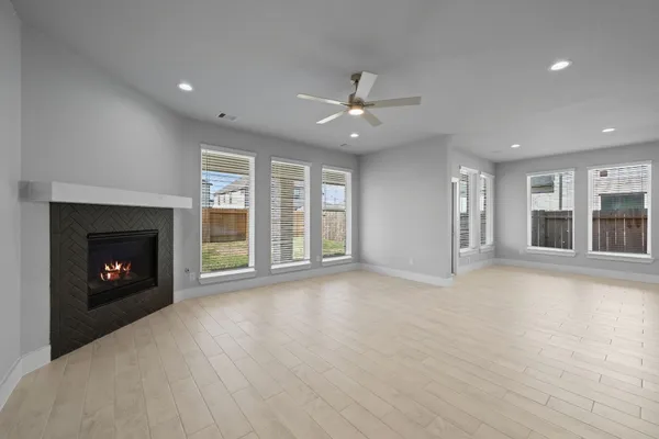 an empty room with windows fireplace and a kitchen view