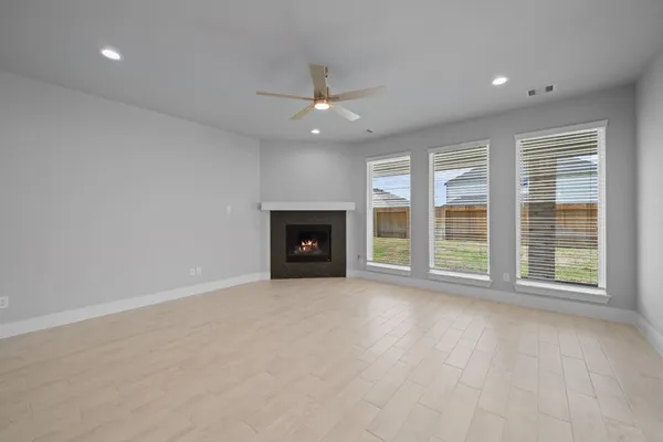 an empty room with windows fireplace and a ceiling fan