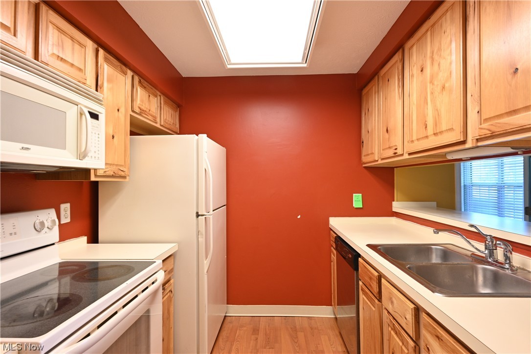 28140 Detroit Road, Unit A1 Westlake, OH 44145 - Photo 11 of 30 Kitchen featuring white appliances, sink, and light hardwood flooring