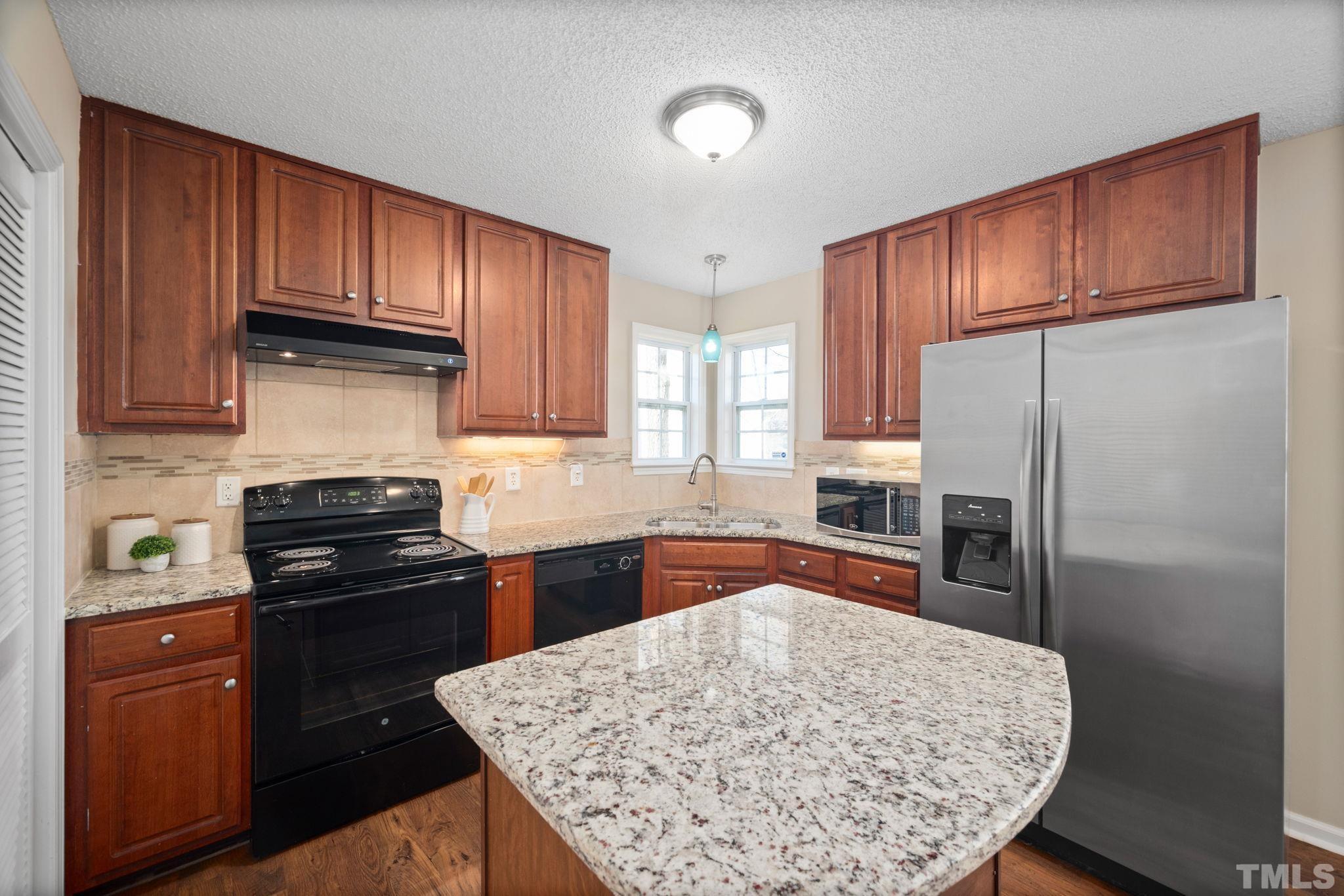 124 Gentle Rio Court Garner, NC 27529 - Photo 18 of 37 a kitchen with stainless steel appliances granite countertop wooden cabinets stove and refrigerator