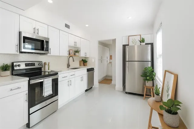 a kitchen with stainless steel appliances white cabinets and a refrigerator