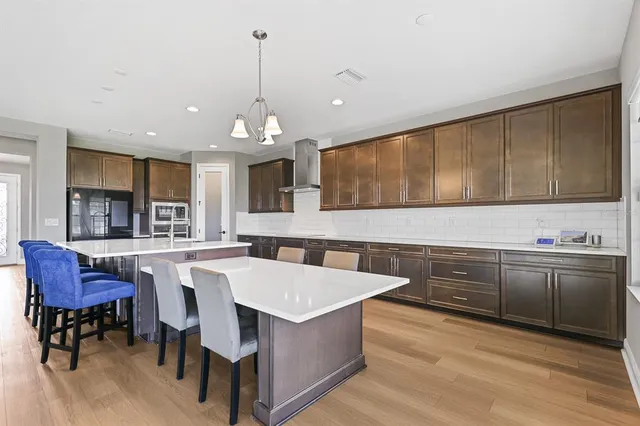 a open kitchen with stainless steel appliances granite countertop a stove top oven a sink dishwasher a dining table and chairs with wooden floor