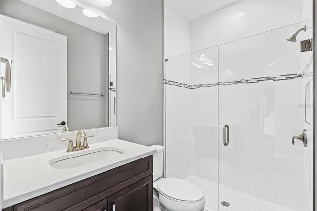 a bathroom with a granite countertop sink toilet a mirror and shower