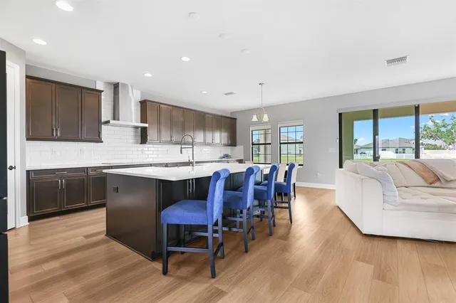a living room with stainless steel appliances kitchen island granite countertop furniture wooden floor and a kitchen view