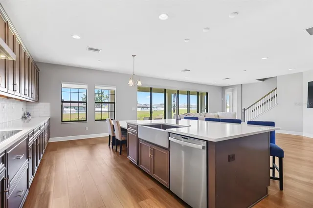 a large kitchen with stainless steel appliances a lot of counter space and a wooden floor