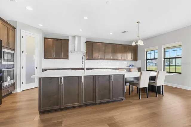 a kitchen with stainless steel appliances granite countertop a stove top oven a sink dishwasher a dining table and chairs with wooden floor