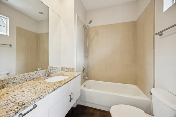 a bathroom with a granite countertop tub sink and mirror with shower