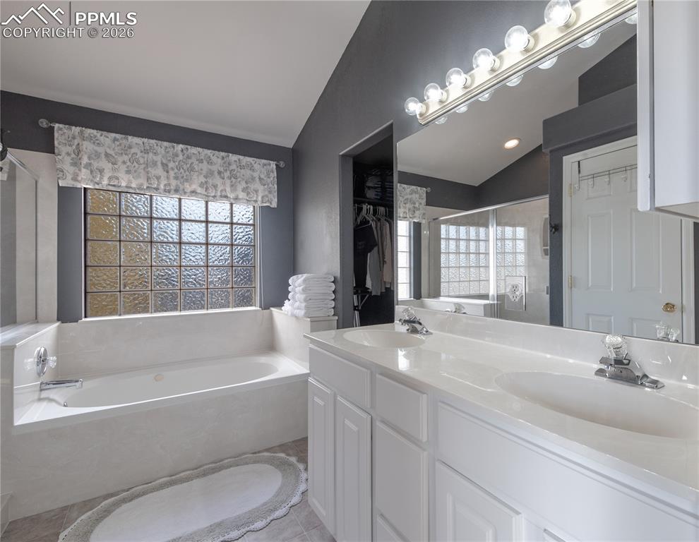 9385 Winged Foot Road Peyton, CO 80831 - Photo 12 of 50 a bathroom with a bathtub a sink and a large mirror
