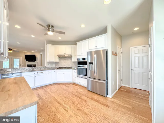 a large kitchen with stainless steel appliances kitchen island granite countertop a refrigerator and a sink