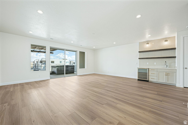 684 West High Tide Place, Unit 131 St. George, UT 84790 - Photo 16 of 27 Spacious room featuring wood-finish flooring, recessed lighting, and a built-in wet bar with a beverage cooler