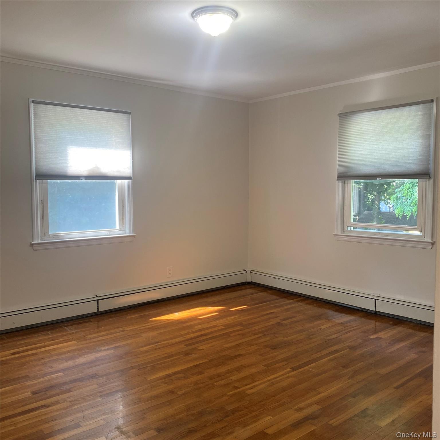 282 Laurel Road, Unit A East Northport, NY 11731 - Photo 12 of 20 a view of an empty room with wooden floor and a window