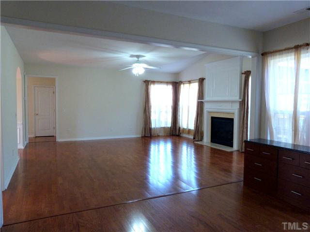 7500 Lagrange Drive Raleigh, NC 27613 - Photo 4 of 20 an empty room with wooden floor and fireplace