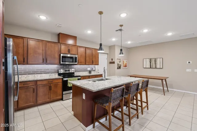a kitchen with stainless steel appliances granite countertop a stove a sink a oven a dining table and chairs